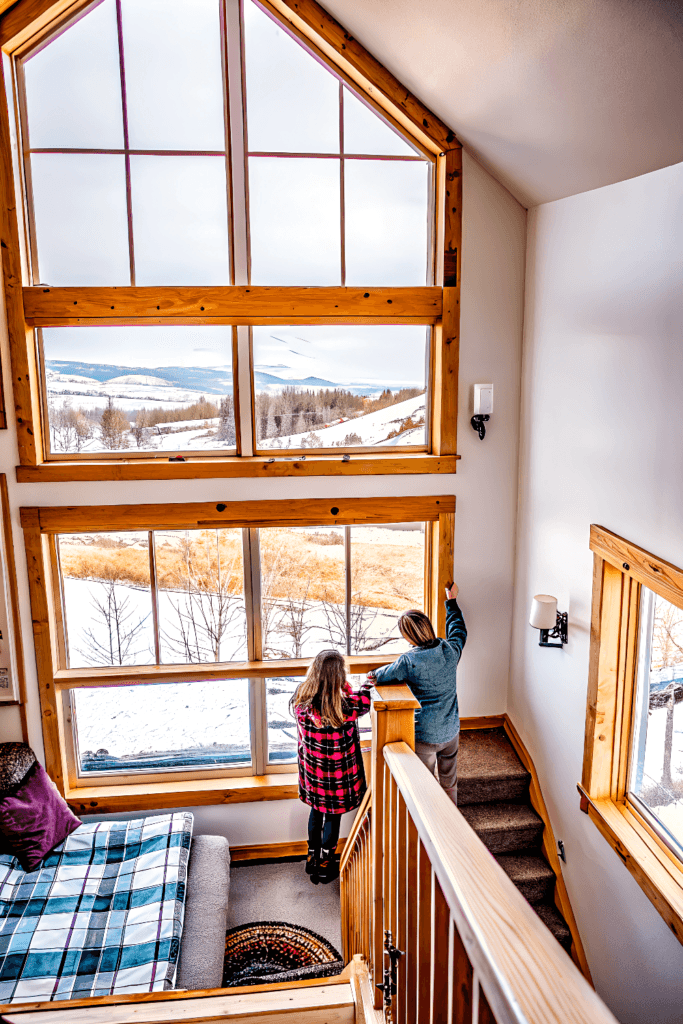 Aspen grove cabin two people looking out of window into a forest snow