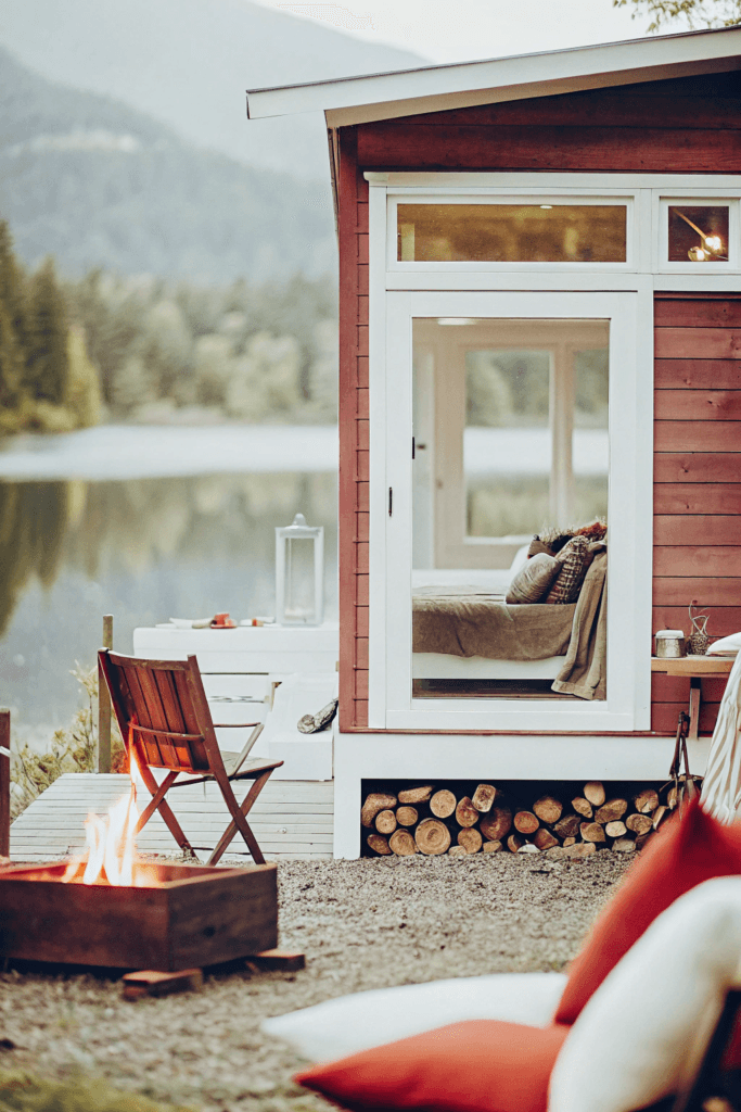 Mountain view retreat A tiny house with a loft bed visible through the window offering views of both the lake and surrounding mountains The outdoor space features a fire pit and comfortable seating