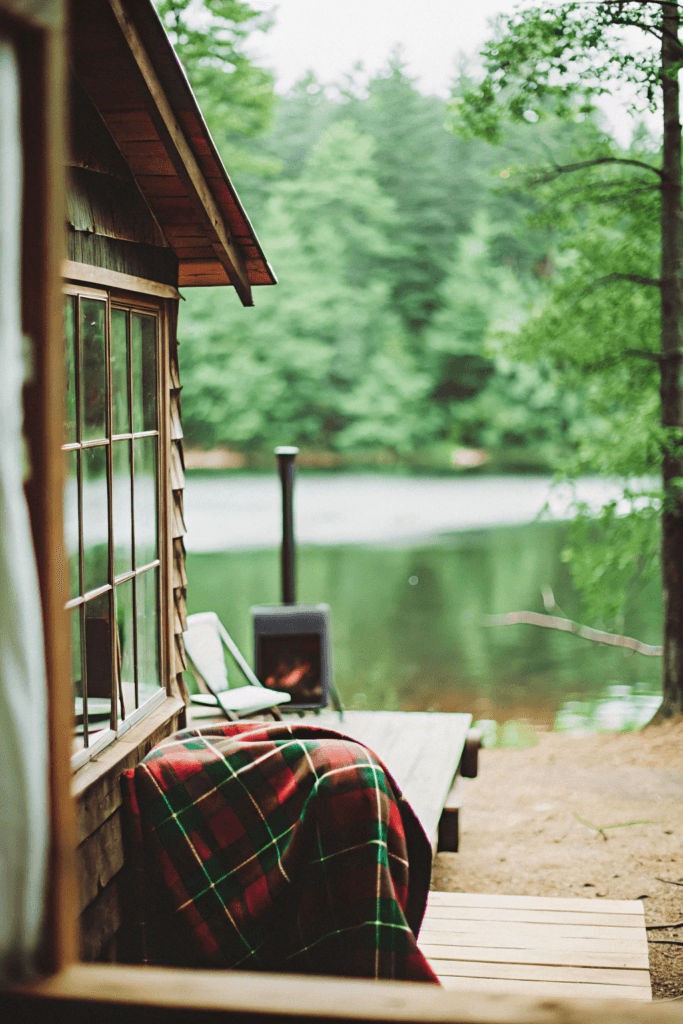 Northern hideaway A cozy cabin surrounded by dense forest with a wood burning stove visible through the window The setting is tranquil with private access to the lake and a sense of solitude