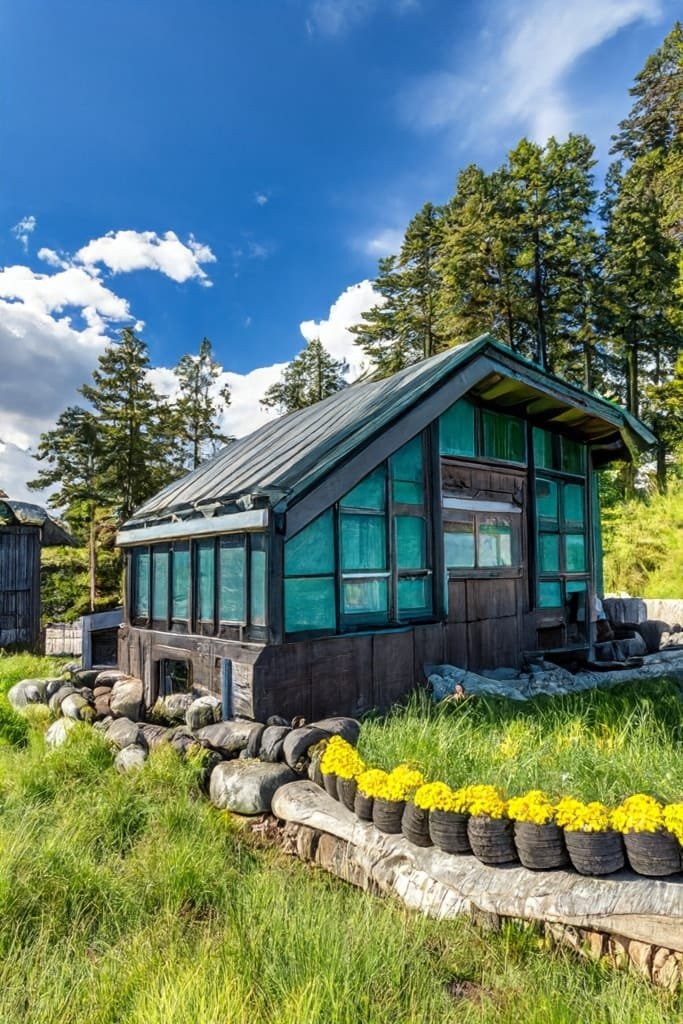Earthship small home on a grassy field, with plant pots