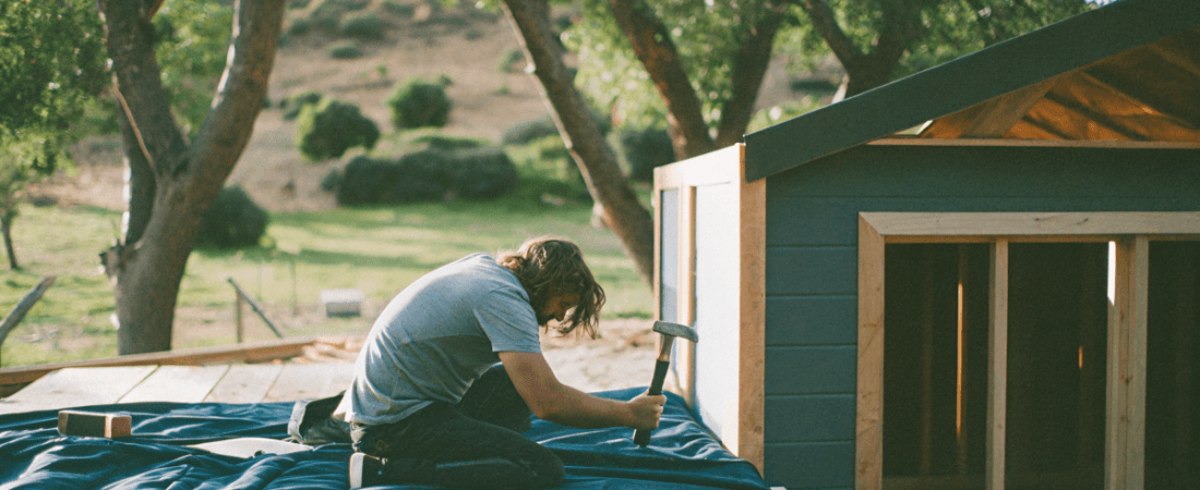 a person making a tiny house and using a hammer
