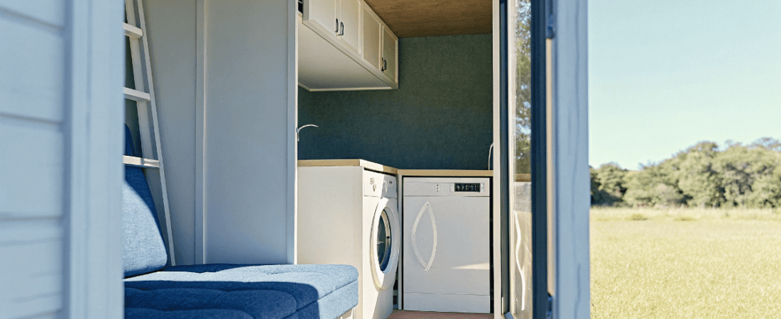 A photo of an interior space within a mobile home The space is compact and designed for functionality featuring a section with a blue seating area a white washing machine