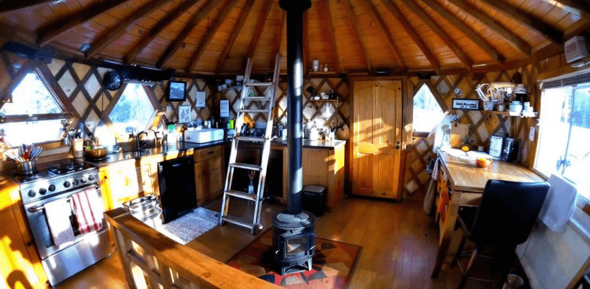 06ff7c5c2bf84851b2108c88a58d79b9 A all wood interior yurt with stove ladder cooker and table