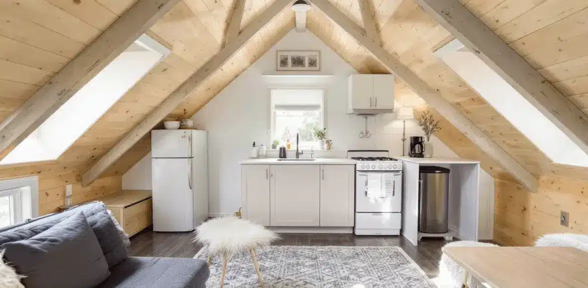 An interior of a tiny barn with exposed beams fridge cooker and sink