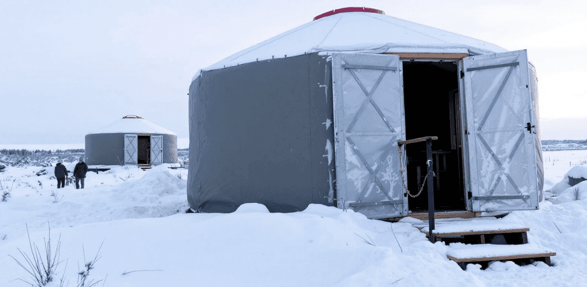 36c5eaf91b4f4f99b41787061282d07e A grey yurt cabin surrounded by snow