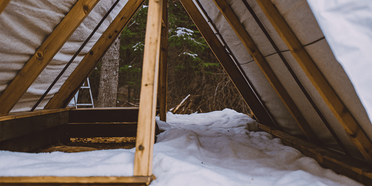 4c73677e0c814830b7ea6ea024738d02 A photograph of a cozy wooden structure specifically a wooden timbered structure resembling a traditional tent with a rustic appearance and natural surroundings