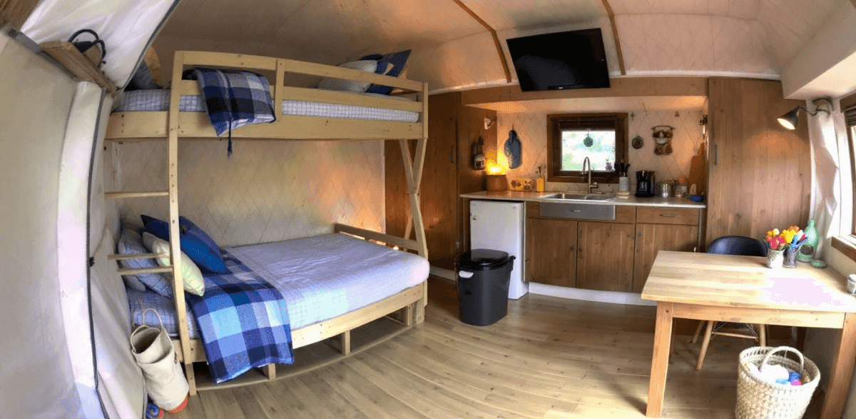 872bc40d593b43b5a1922fac844a9051 An interior of a cozy family yurt with a bunk bed sink table and TV