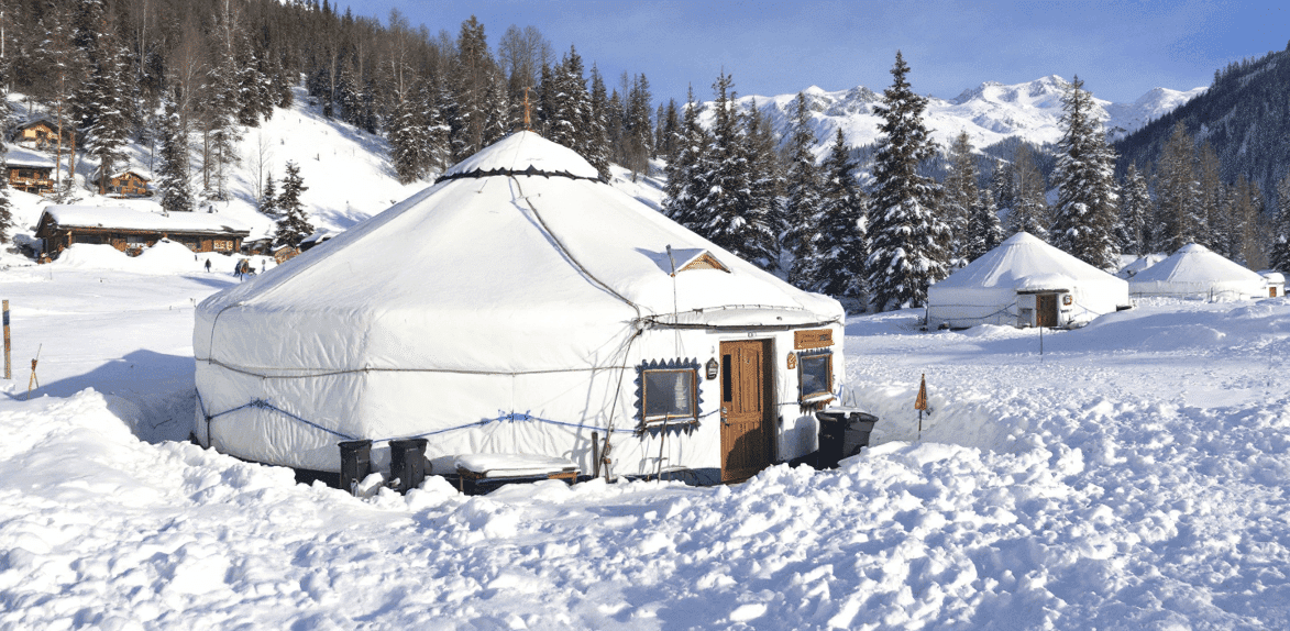 C74c2be805ae4738a84e9b36305c75b1 Yurt huts surrounded by snow next to mountains