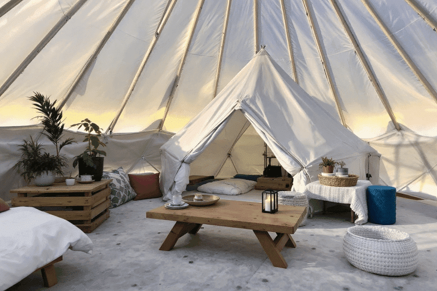 Cfae29f56a154828bf7ff37f081f4f63 A photograph of an indoor space resembling a tent like structure featuring various decorative elements The space is warmly lit with a cozy and rustic atmosphere