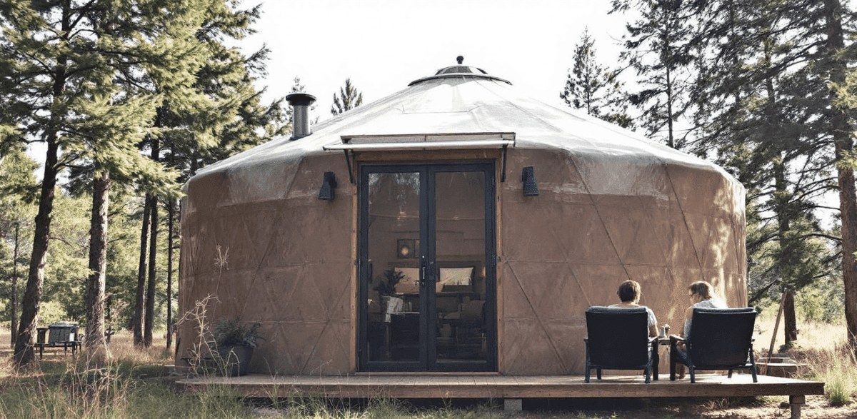 D808c40458fe44ea9a1bc67afcd02ae1 Two people sitting on chairs outside a yurt