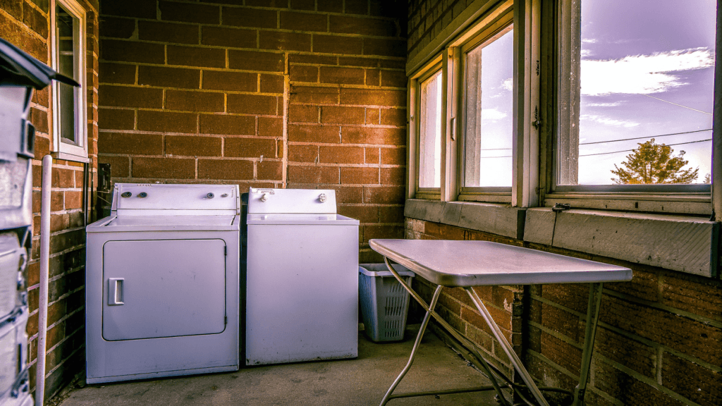 Faux brick A laundry area with a washer and dryer beside a folding table and window showing trees