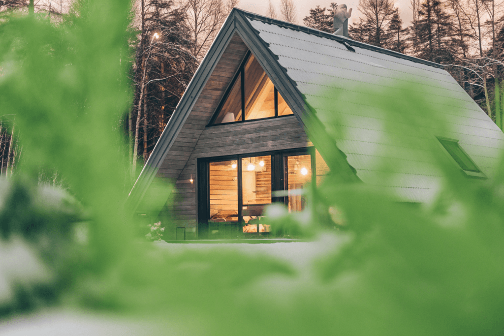 Aframe cabin Photograph of a modern A frame cabin nestled in a serene snow covered winter forest at dusk with a family enjoying the warm illuminated interior
