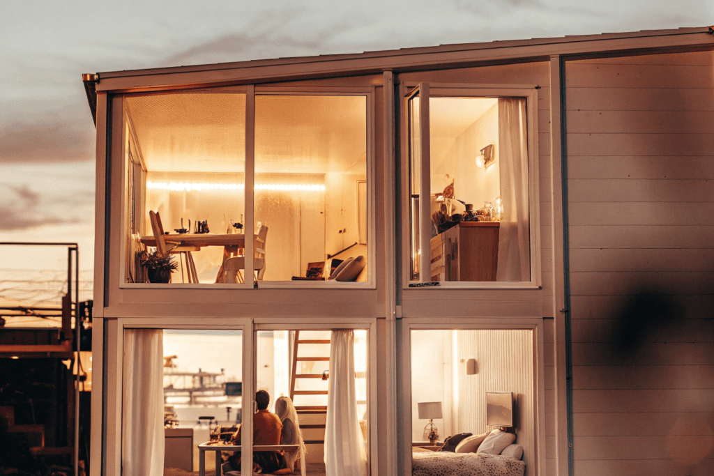 Lofted library Photograph of a modern multi functional tiny house at dusk showcasing different living and working spaces with people engaging in various activities emphasizing efficient and comfortable living