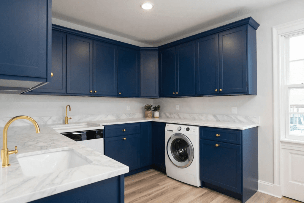 Laundry room with navy blue cabinets marble countertops and brass hardware