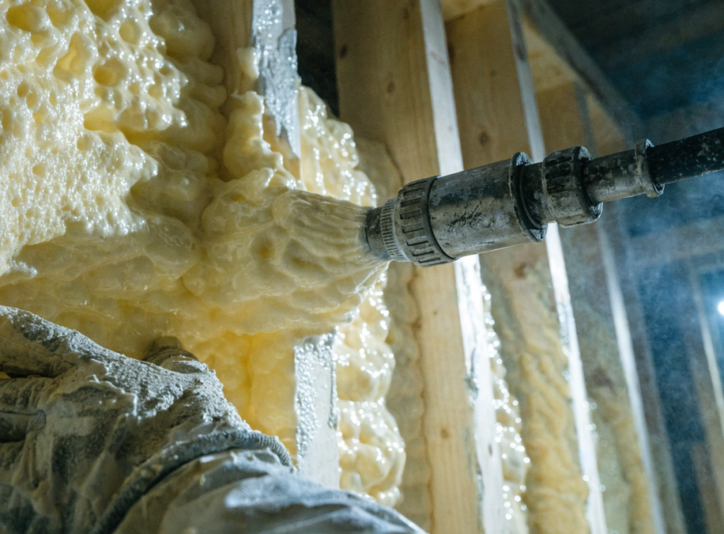 Closed cell spray foam Open wall view of beige spray foam insulation expanding around a metal pipe
