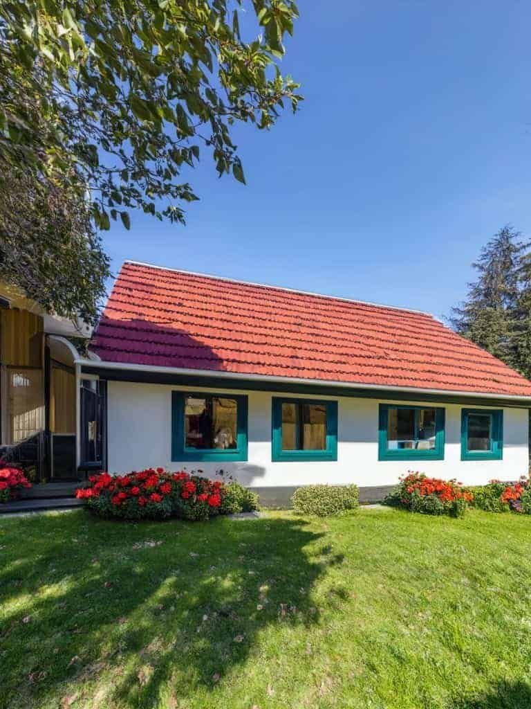 Charming tiny house with red roof Cozy tiny house with red roof white walls and green window frames in a lush garden