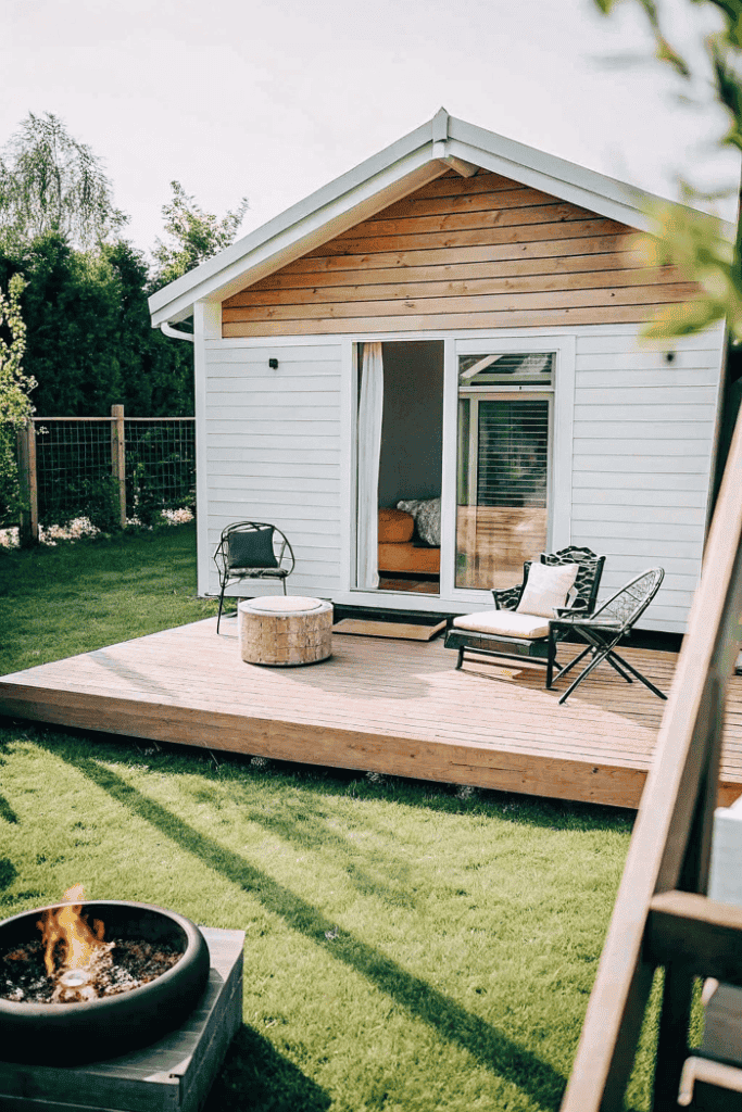 Explore tiny house exterior view Charming tiny house with wooden deck and outdoor seating in a lush garden